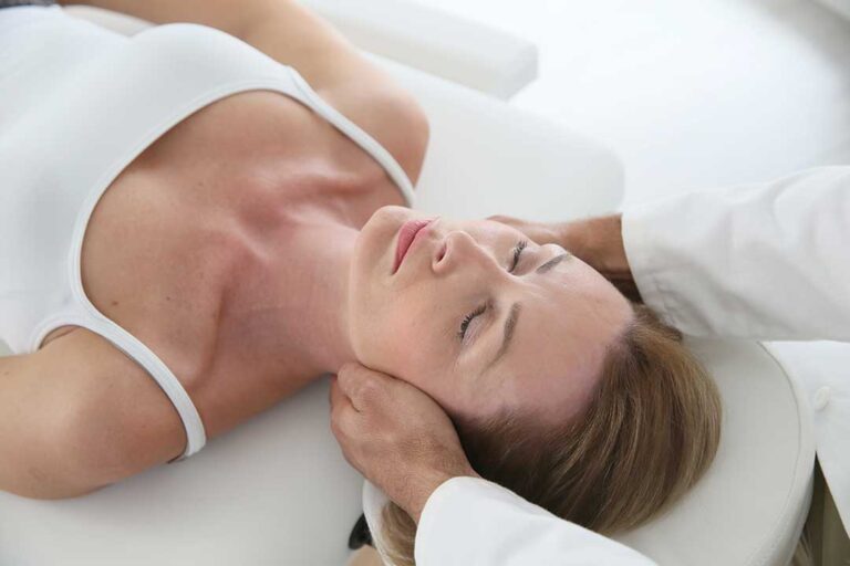Person recording pain symptoms beside a heating pad, water bottle, and stretching mat at home.