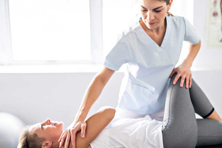 Person gently massaging the jaw while seated at a desk with relaxed neck and shoulder posture.
